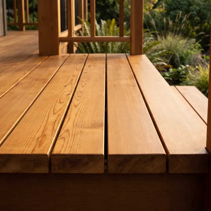 Freshly oiled cedar deck boards, the grain sharp and open and the surface holding a low satin sheen.